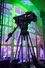 professional video camera on a tripod in a room with club light. professional videography
