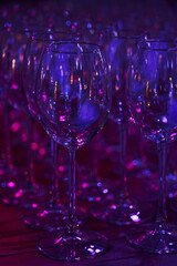 lots of empty wine clear clean glasses in neon light
