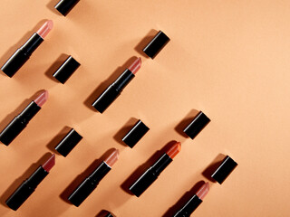 Creative pattern fashion photo of cosmetics beauty products lipsticks on a orange background
