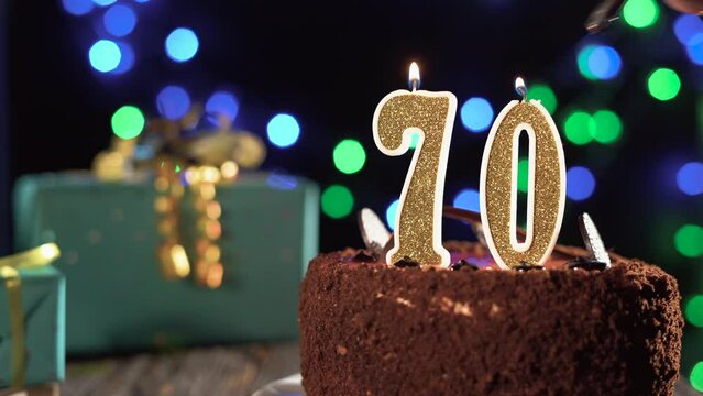Number seventy birthday candle on sweet cake on the table, 70th birthday. Fire from the lighter, blow out the holiday candle.