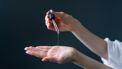 Close Up Shot of a Caucasian Hand Holding an Eye Dropper While Dropping Some Serum Into Her Palm...
