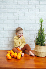 Cute smiling kid eating one fresh juicy tangerine