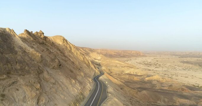 Aerial view of a winding road on a mountain side in the desert at sunrise. Paran river, Negev, Israel