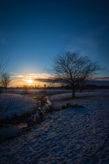 Snow covered landskape during sunset with stream and tree in Sk&aring;ne (Scania) Sweden