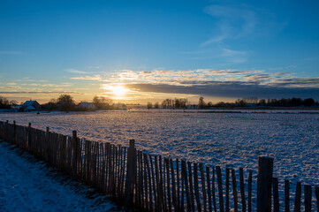 Obraz premium Sunset over snow covered flat farmfields with fence in Skåne (Scania) Sweden