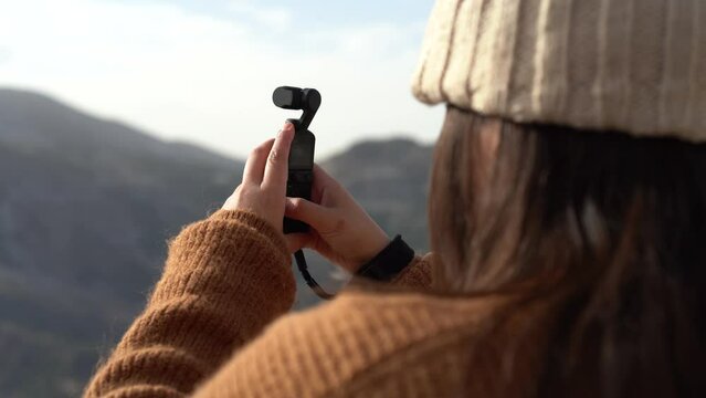 Chica joven guapa tomando video con dispositivo en una monta&ntilde;a nevada