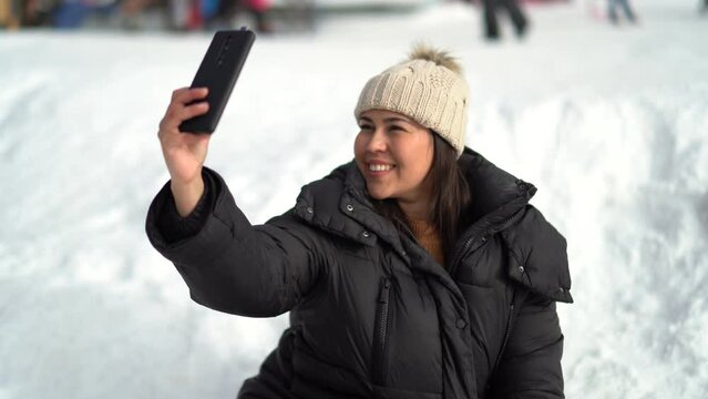 Chica joven guapa sonriendo mientras se toma fotos en la nieve