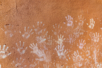 Multiple colorful children hand prints on huskily brown wall