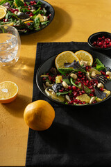 Fresh salad with orange and pomegranate seeds, spinach on yellow background. Vertical