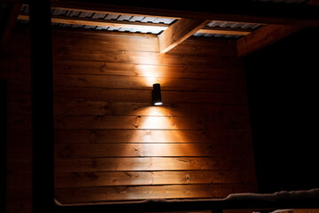 Bright street lamp with double light. Lighting on the streets near the house. Wooden walls of the...