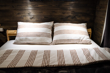 Fototapeta na wymiar Paired pillows made of soft fabric with a geometric pattern. Cozy wooden room,Deep sleep. The dim light in the wood room. Cotton bed linen.