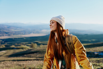 woman in a yellow jacket in a hat backpack travel mountains relaxation