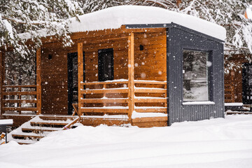 Modular house made of dark metal and light wood in winter forest. a house that takes into account...