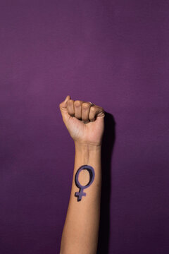 Woman raises her fist with a feminist symbol on her forearm, fights for gender equality, feminism, female power