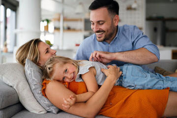 Parents having fun with their little daughter on bed. Family spending time at the morning.