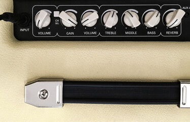 Hand adjusts combo amplifier for guitar with electric guitar on the black background. Shallow depth...