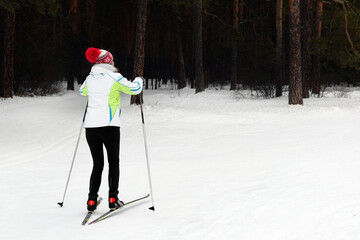 Young girl is skiing in a dark forest. Active rest and healthy lifestyle.