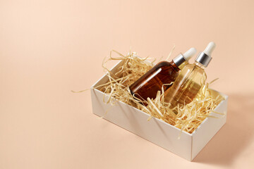 Natural cosmetics in glass bottles with a dropper in a packaging box on a beige background. The concept of natural cosmetics, natural essential oil
