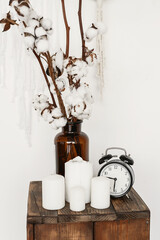 Vase with cotton branches and beautiful candles on table in room. Cozy and soft home decor concept