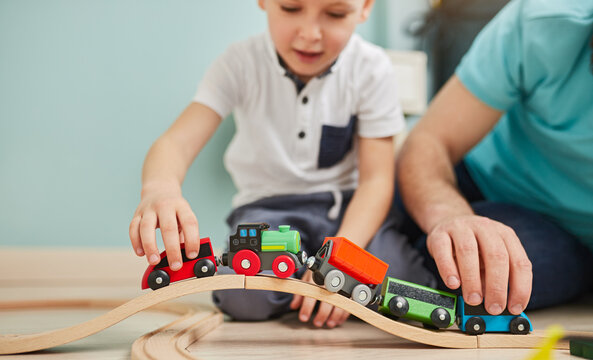 Crop Child And Father Playing With Wooden Railway At Home