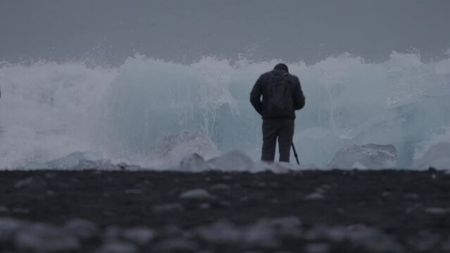 Spectacular waves breaking over huge iceberg with tourist
