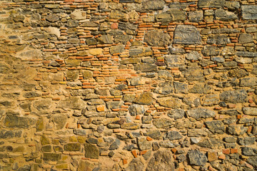Brick and stone wall in warm tones of an ancient medieval wall. Concept with highly textured backgrounds.