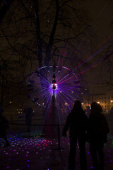 Vilnius, Lithuania - January 28, 2022: Disco ball reflects Lazer lights in Park at Vilnius Light Festival. Popular colorful light installation at celebration at night. The explosion of the universe 
