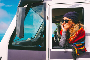 Cheerful and happy adult pretty woman outside the window of her camper van motorhome enjoy...