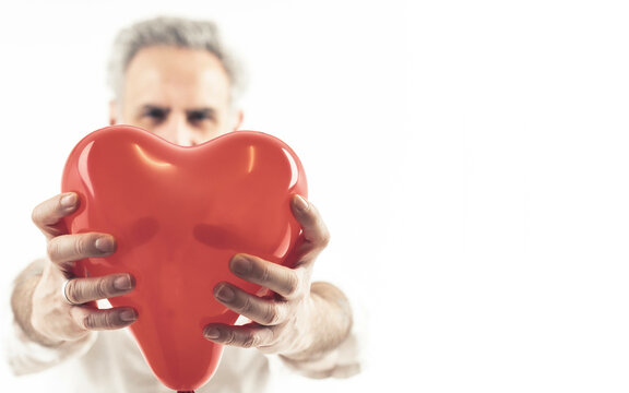 Grey haired man holding heart shaped baloon - isolated on white background. High quality photo