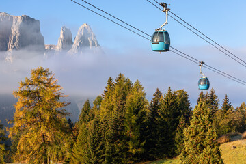 Cable car cabins over the autumn trees at the foggy morning in Seiser Alm. South Tyrol, Italy. © Artem