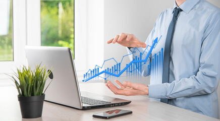 Business man holding tablet and showing holographic graphs and stock market statistics gain profits. Concept of growth planning and business strategy. Display of good economy form digital screen.