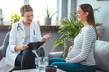 Pregnant Woman Speaks With Her Doctor at a Check-Up. A woman discuses her prenatal health during a routine check up with her obstetrician.