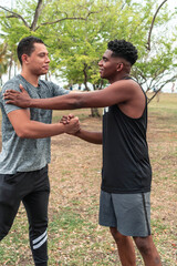 Men in sportswear in the park shaking hands with smiling faces