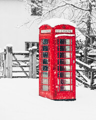 Red telephone box  covered in snow, isolated against a black and white background