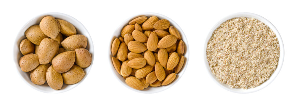 Almonds in white bowls. Whole, dried nuts of Prunus dulcis, with and without shells, ready to eat as a snack, and ground nuts, used for baking. Isolated, from above, on white background, food photo.