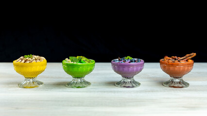 Smoothies or puddings with kiwi, bannas, blueberries and chocolate with almonds and hazelnuts in a crystal bowls