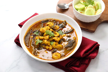 Tangy and spicy Shrimp curry. Tiny prawns curry made using dried mango and Indian spices. garnished with coriander and served with cucumber slices. Copy space.