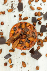 Smoothie or pudding with chocolate, hazelnuts and almonds served in a bowl for breakfast. Flat lay image