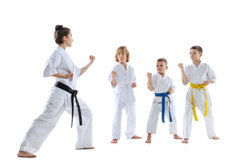 Group of kids, boys, taekwondo athletes wearing doboks training with master isolated on white background. Concept of sport, martial arts