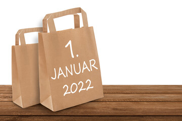 Papiertüten und Datum 1. Januar 2022 auf Holz  mit weissem Hintergrund