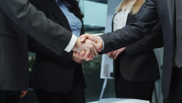 Business partners shaking hands after reaching agreement. Partial view top managers making deal in office. Concept of success