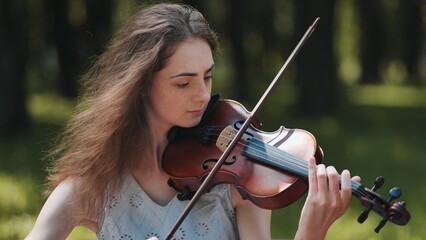 A young girl plays the violin in the city park. © Довидович Михаил