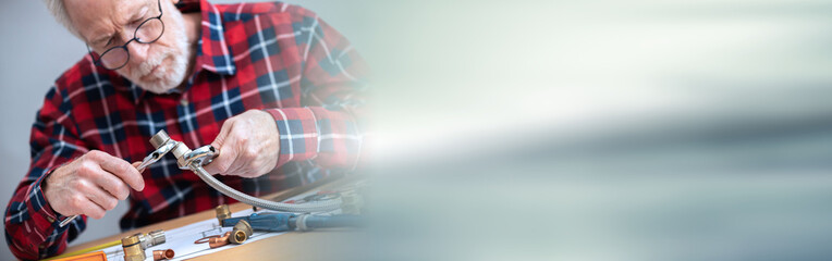 Plumber screwing a plumbing fitting; panoramic banner