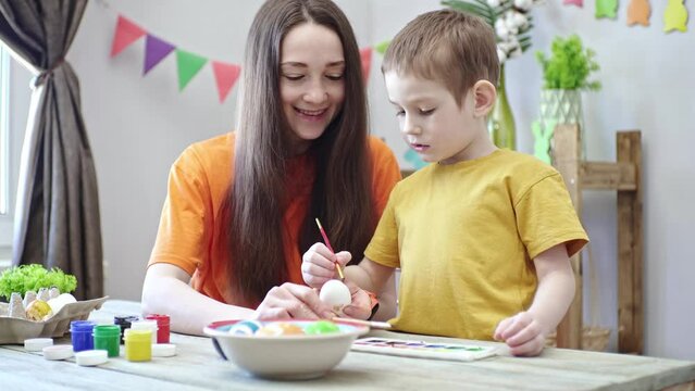 Mom and a child together are coloring eggs and having fun. Concept of family preparation for Easter, festive spring mood