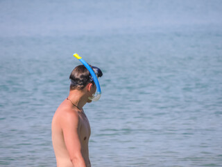 A young man with a mask and snorkel for diving under water. Diving underwater with a mask and snorkel at sea. Underwater diving. A swimmer looks into the sea.