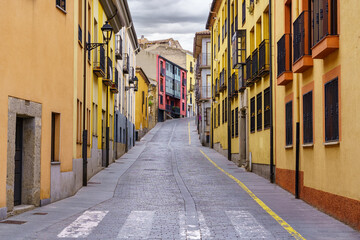 Narrow alley with colorful houses and balconies in the old town of Avila, Spain.