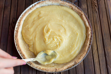 Preparation for the pie - shortbread dough after baking, filling with lemon curd, cream, in a round shape