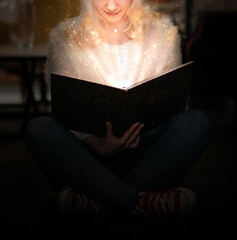woman is reading a book in the library. Magic light, fantasy