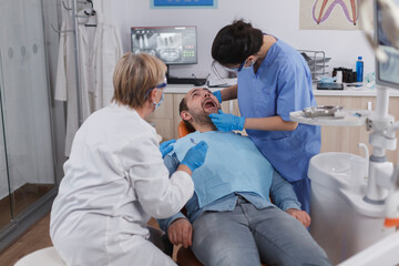 Naklejka na ściany i meble Dentist woman nurse checking patient mouth analyzing teeth infection using stomatological drill instrument during orthodontic examination in dental office room. Concept of dentistry procedure