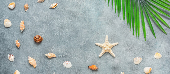 Abstract beach summer background. Decorative palm leaves, shells and starfish on a gray concrete grunge background. Top view, flat lay, banner.